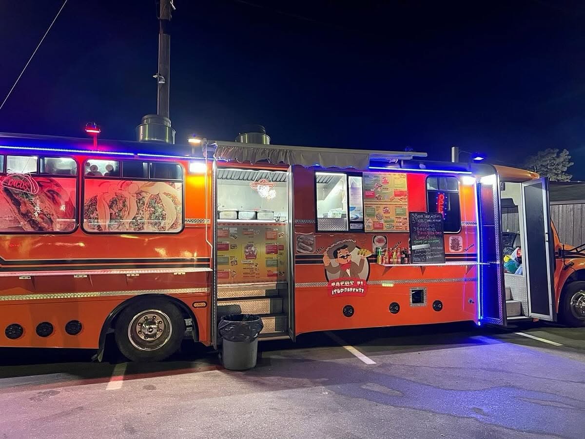 The Tacos El Iturbidense food truck lit up with neon at night